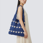 Woman styling a blue slouchy knit beach bag with a relaxed summer outfit