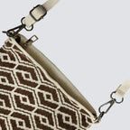 Adjustable strap and hardware detail of a brown patterned knit crossbody bag