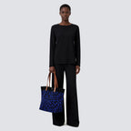 Woman carrying a dark blue patterned knit tote bag with a casual everyday outfit