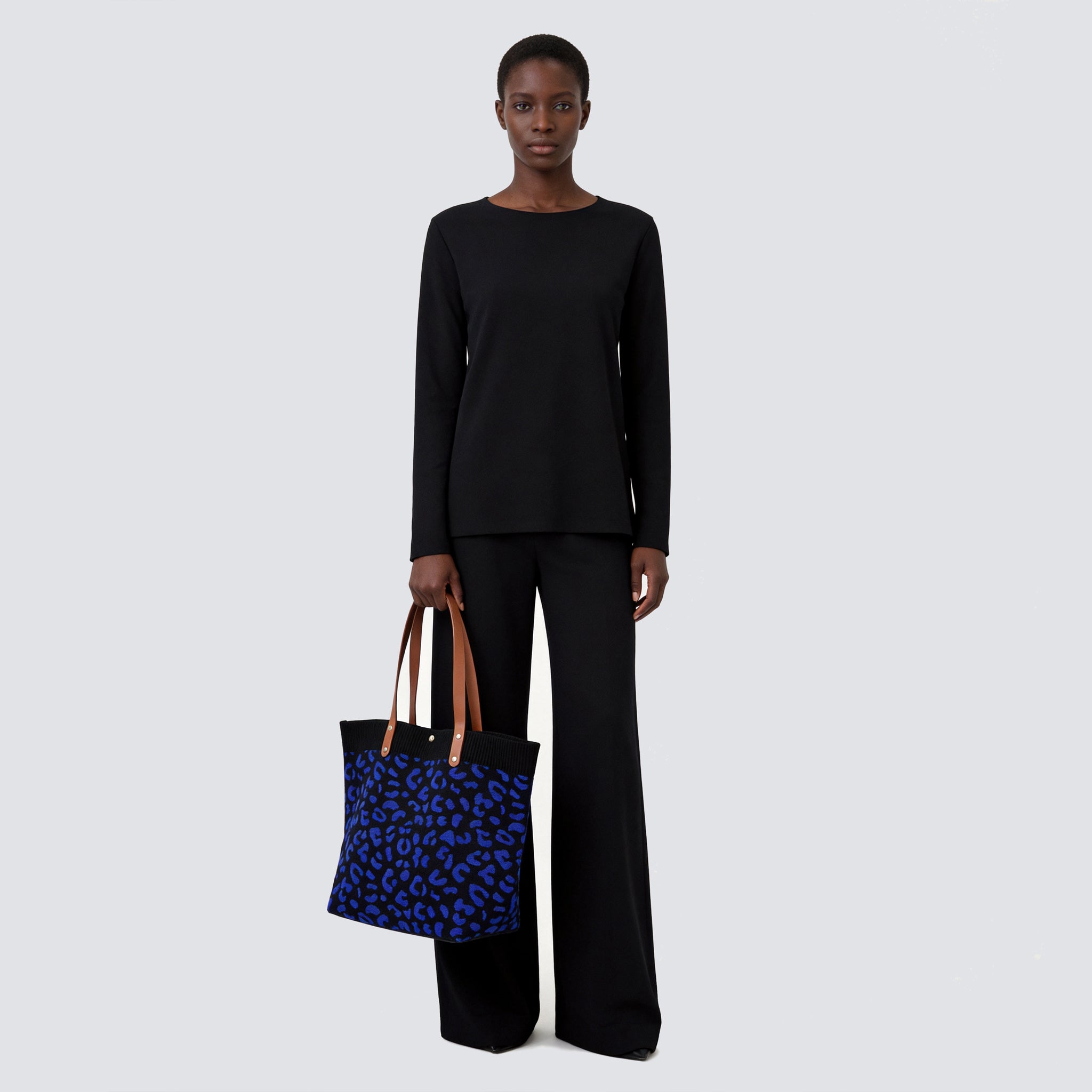 Woman carrying a dark blue patterned knit tote bag with a casual everyday outfit
