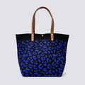 Dark blue patterned knit tote bag with brown handles on a simple product background
