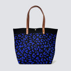 Dark blue patterned knit tote bag with brown handles on a simple product background