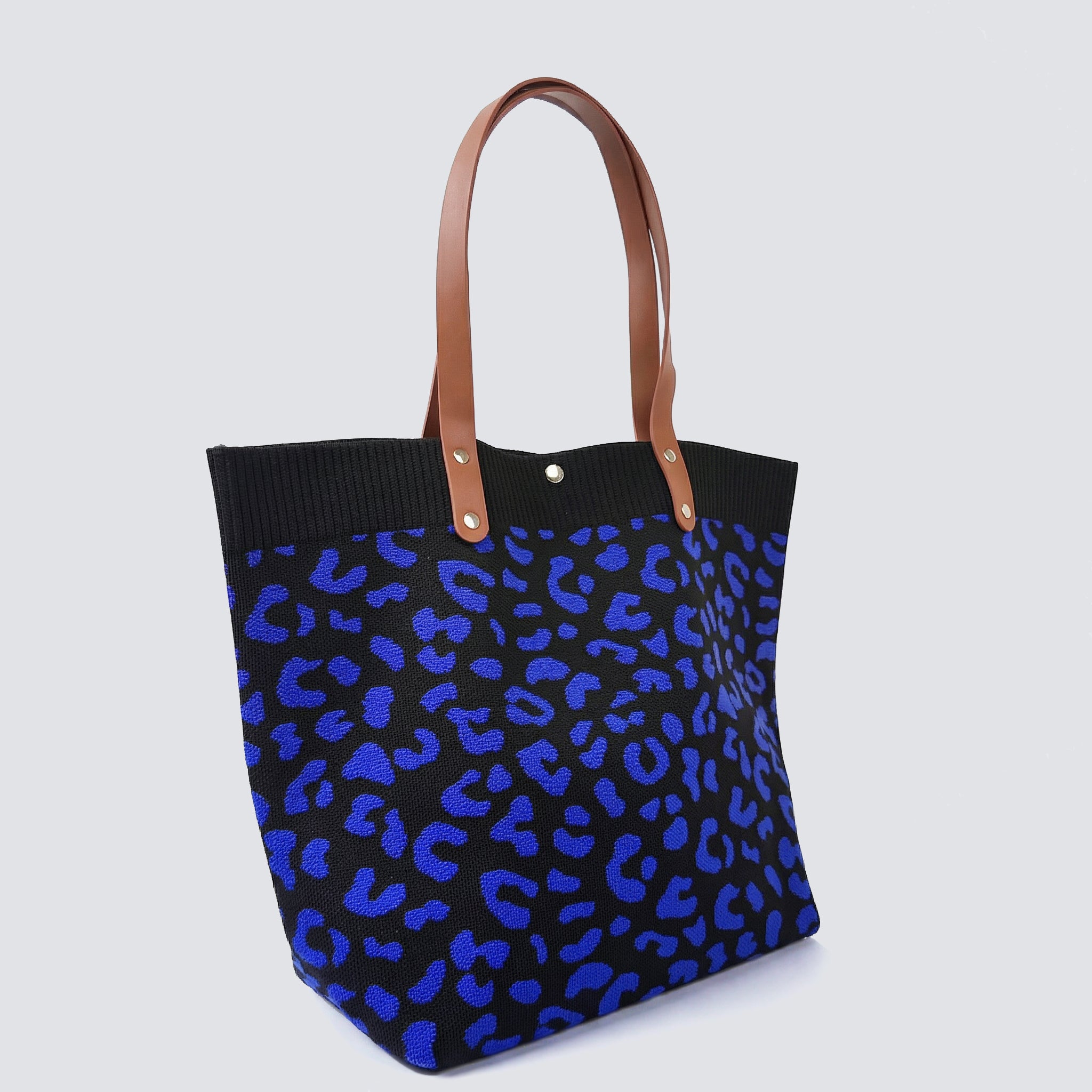 Side view of a dark blue patterned knit tote bag with brown handles