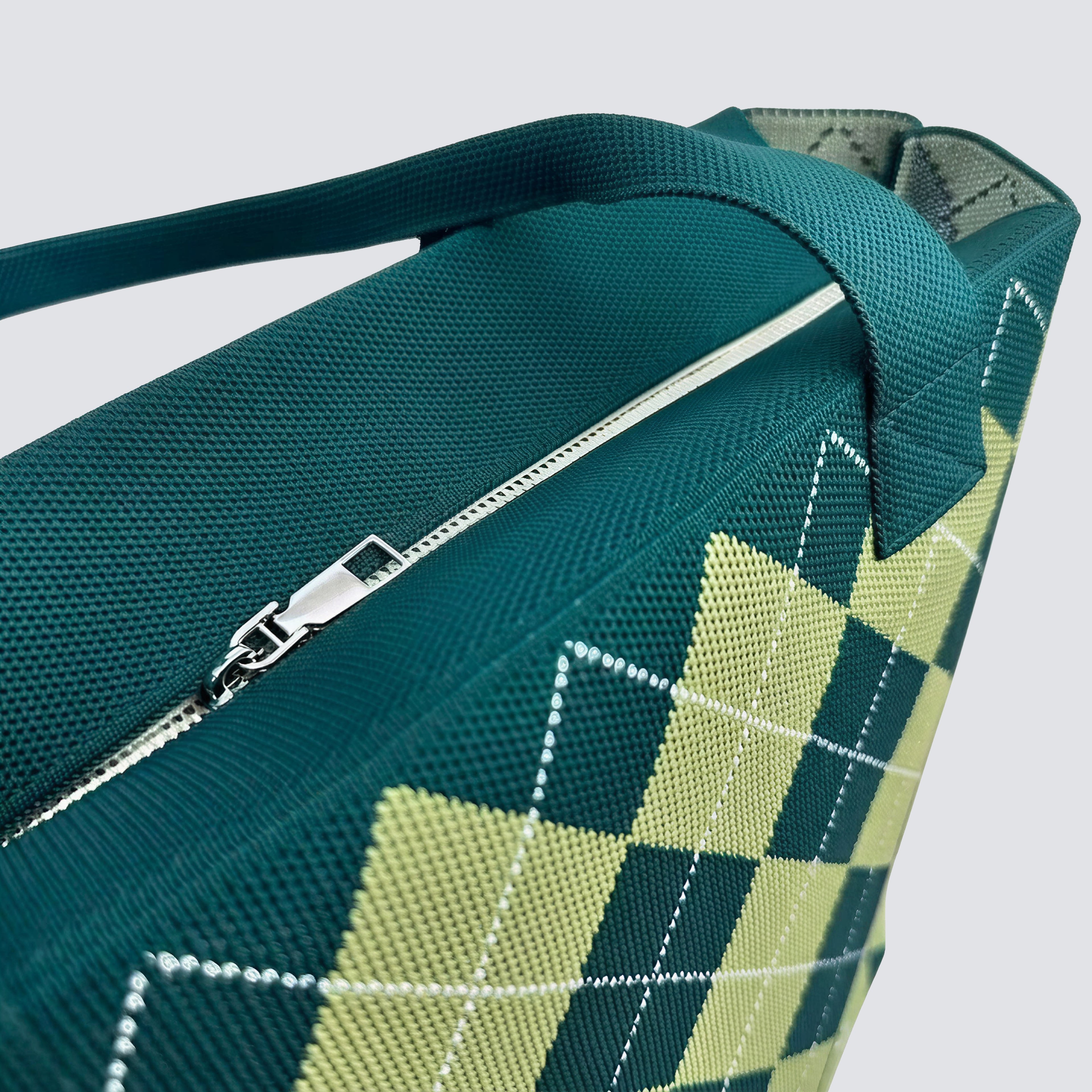 Close-up detail of the green argyle knit tote bag pattern and handle