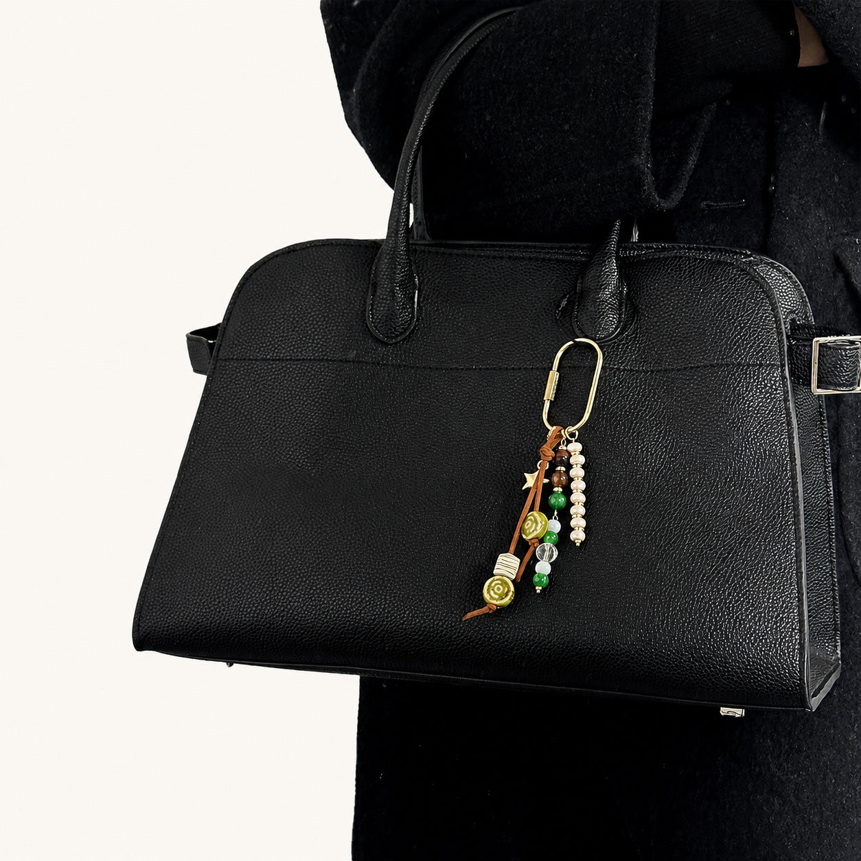 Green and white beaded bag charm with ceramic beads hanging from a black handbag