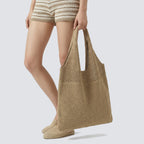 Khaki striped slouchy knit beach bag worn over the shoulder in a casual warm-weather look