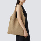 Woman styling a khaki striped slouchy knit beach bag with a relaxed summer outfit