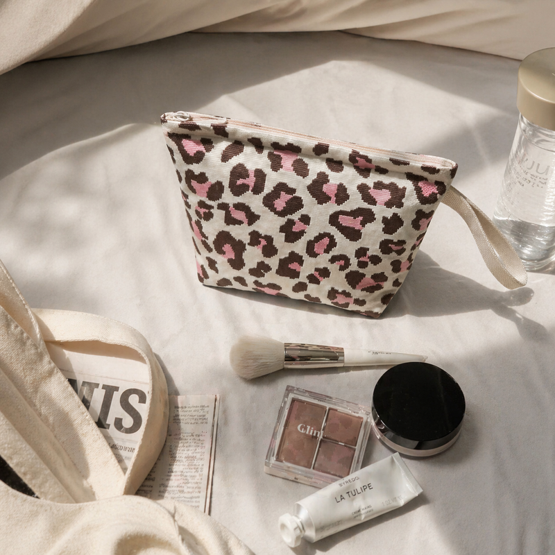 Leopard print mini pouch styled with everyday essentials on soft bedding