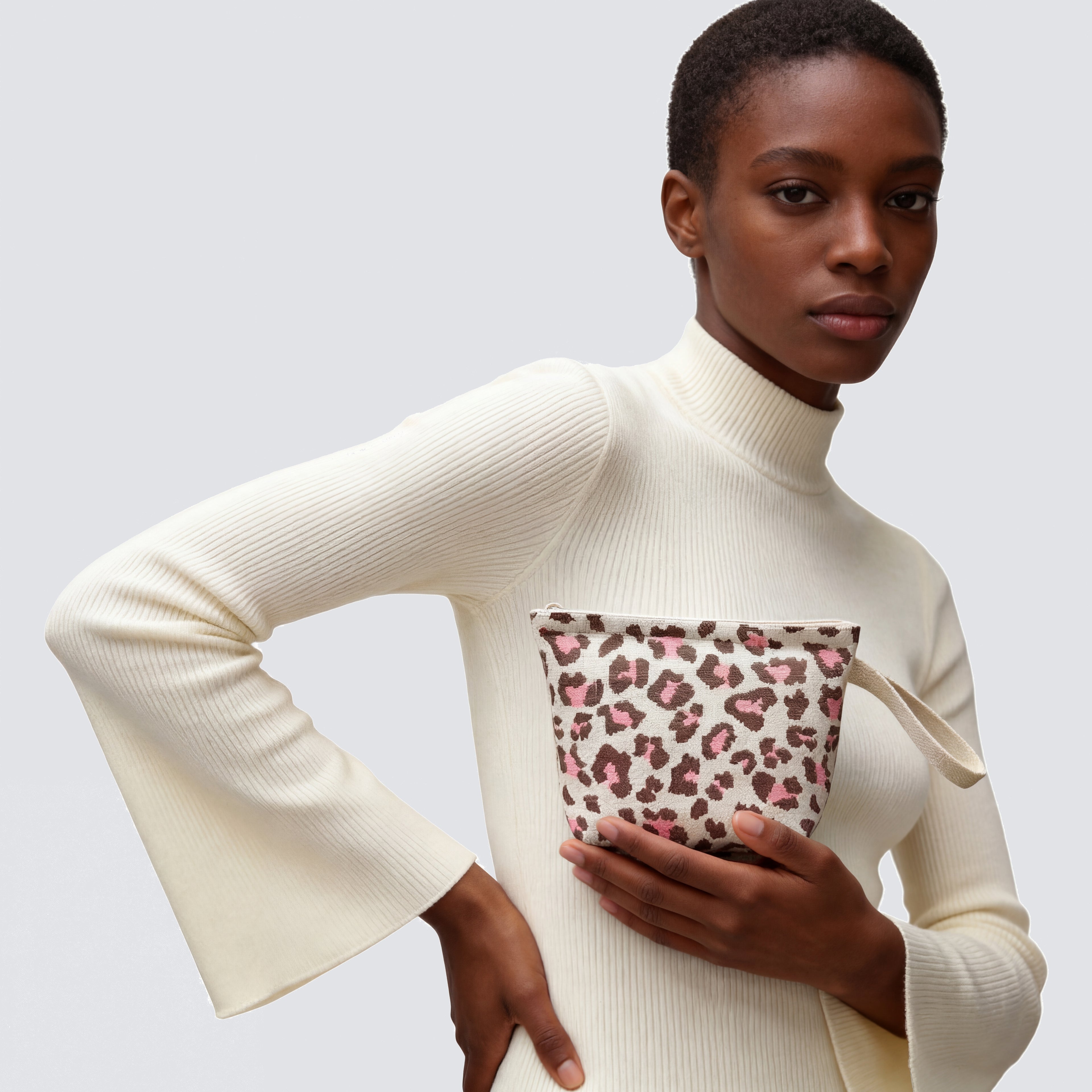 Woman carrying a leopard print knit mini pouch and makeup bag with a casual outfit