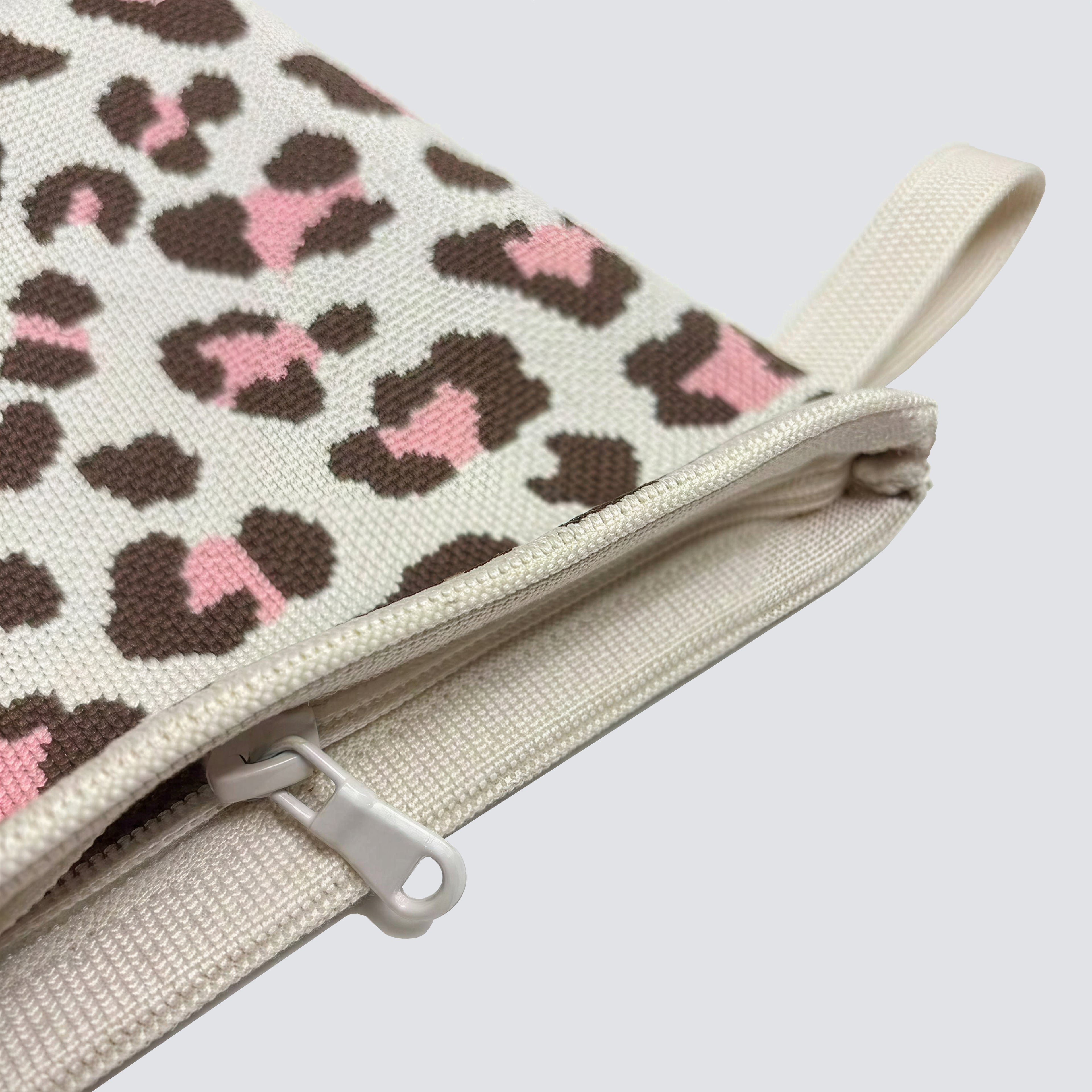 Close-up of the leopard print knit texture and zipper on a mini pouch makeup bag