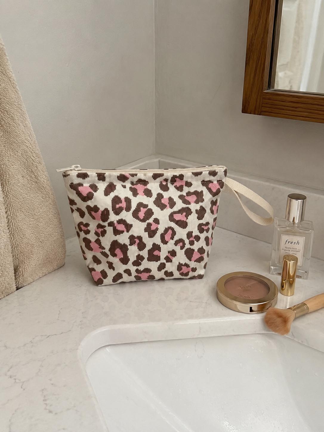 Leopard print knit makeup bag on a vanity with perfume and cosmetics