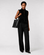 Woman wearing The Onyx black woven vegan leather shoulder bag as a crossbody with an all-black outfit