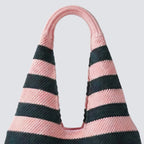 Side view of a pink and navy blue striped knit beach bag with wide shoulder straps