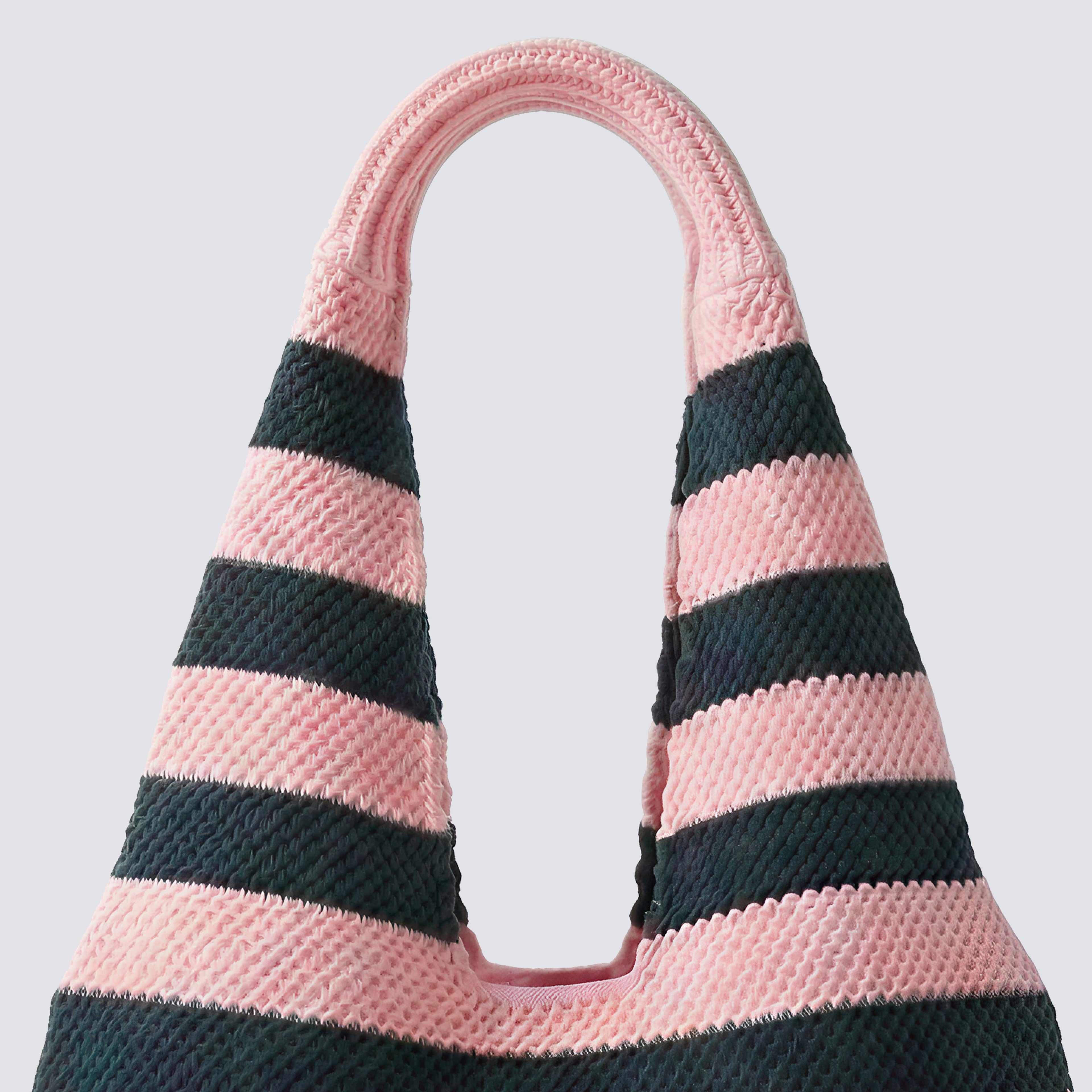 Side view of a pink and navy blue striped knit beach bag with wide shoulder straps