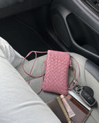 Pink woven vegan leather phone pouch styled in a car lifestyle scene