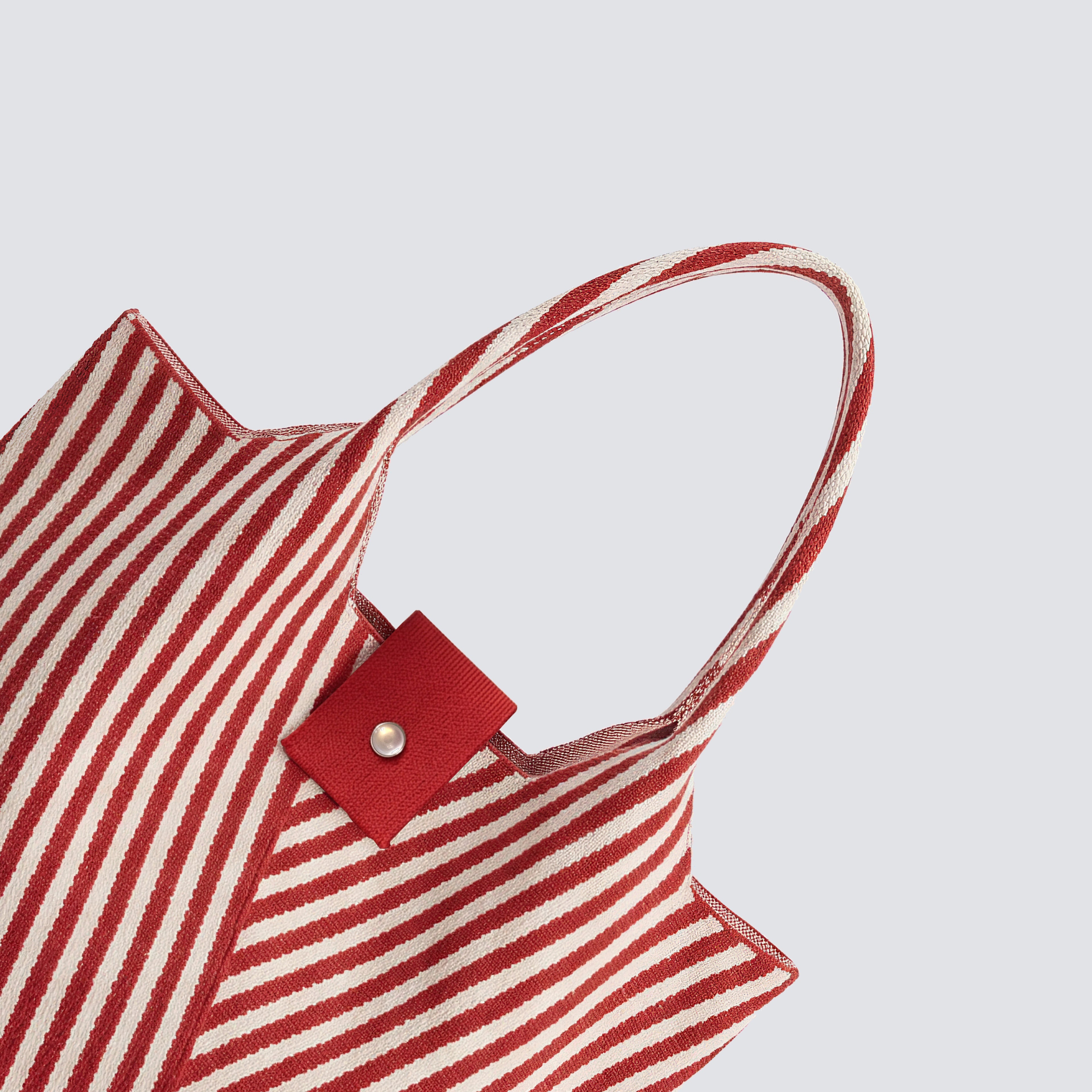 Side detail of a red and white striped knit summer tote bag with short handles