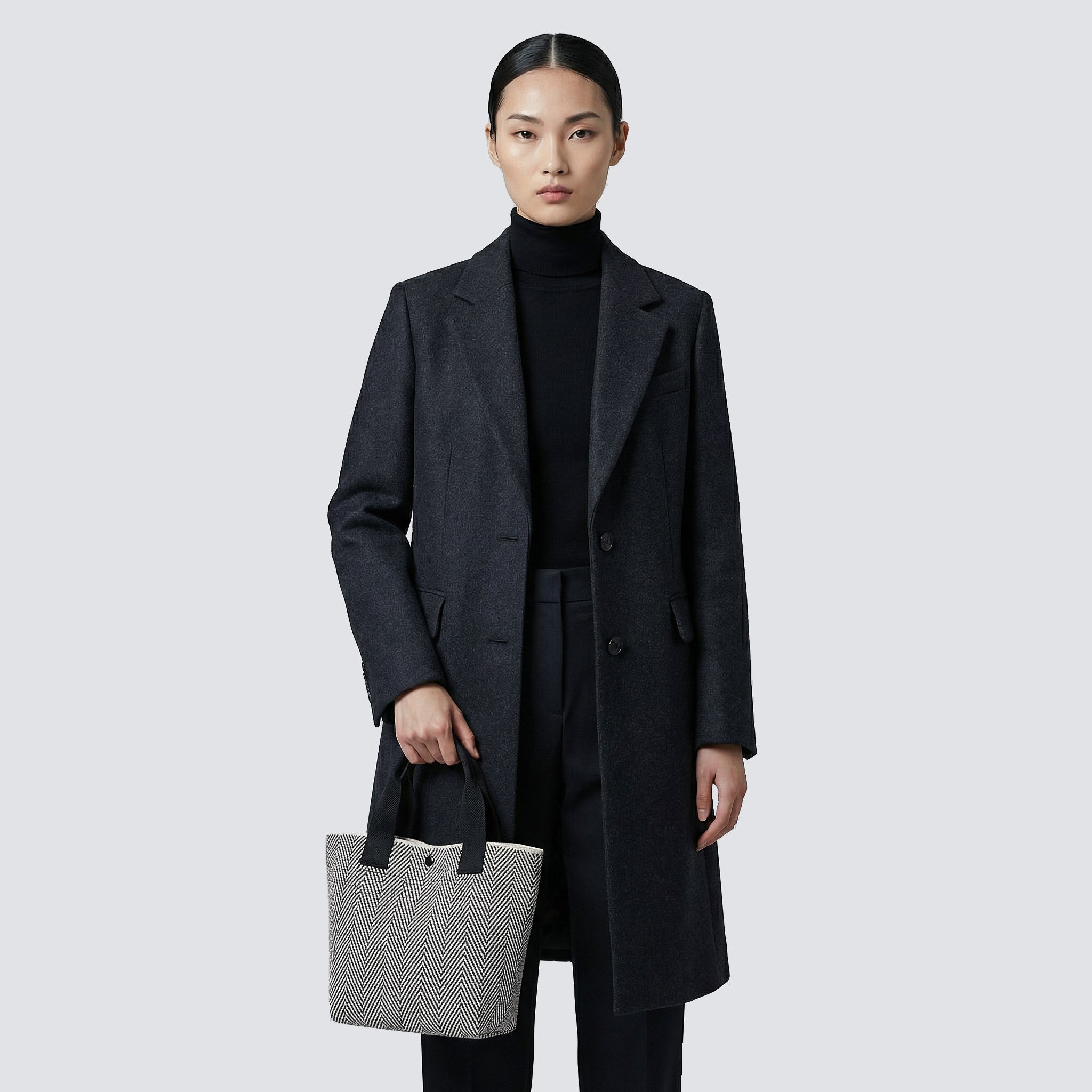 Woman carrying a textured black and white knit tote bag with a minimalist everyday outfit