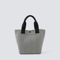 Textured black and white knit tote bag with black handles on a simple product background