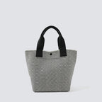 Textured black and white knit tote bag with black handles on a simple product background