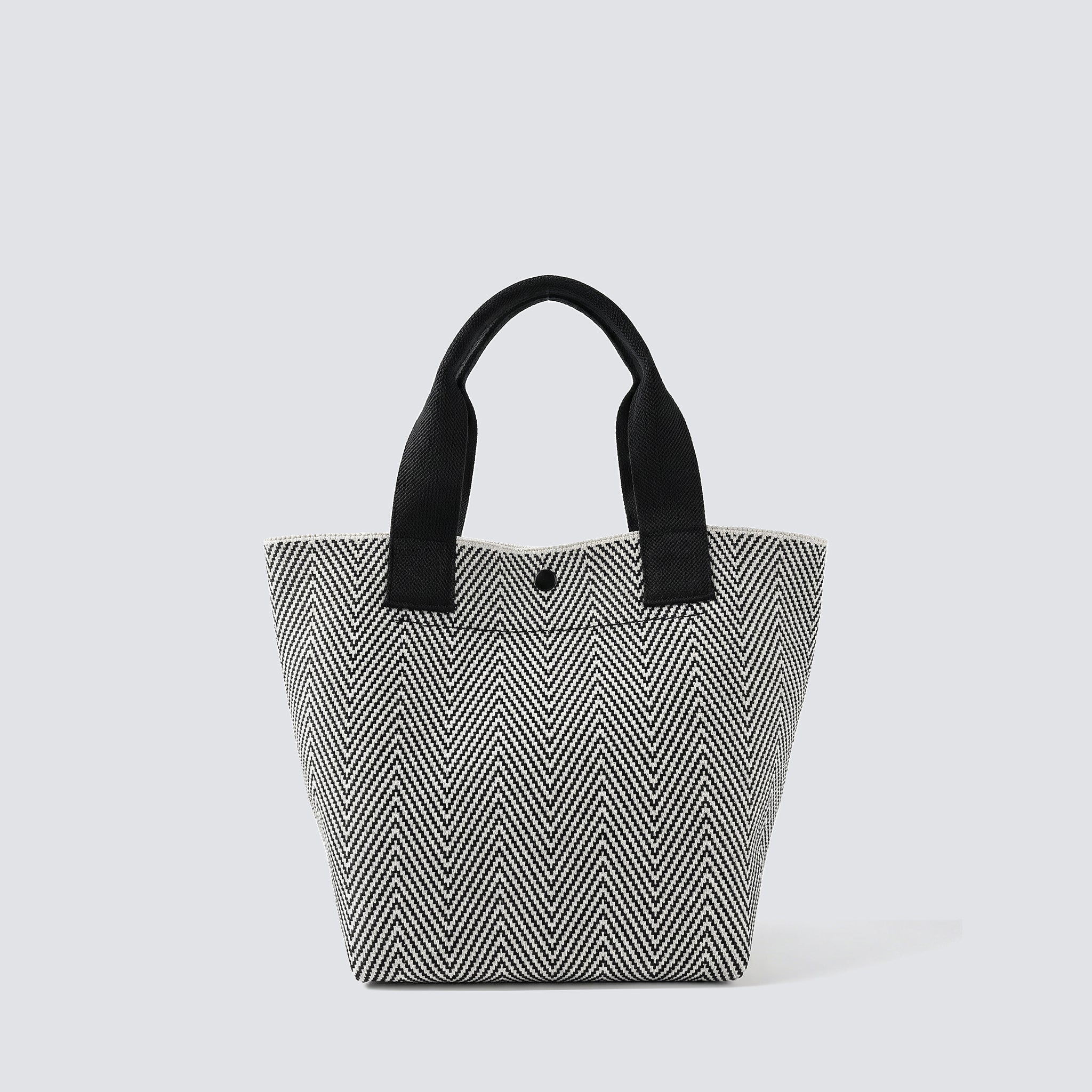 Textured black and white knit tote bag with black handles on a simple product background