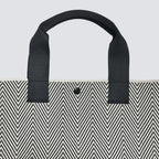 Black handle detail on a textured black and white knit tote bag