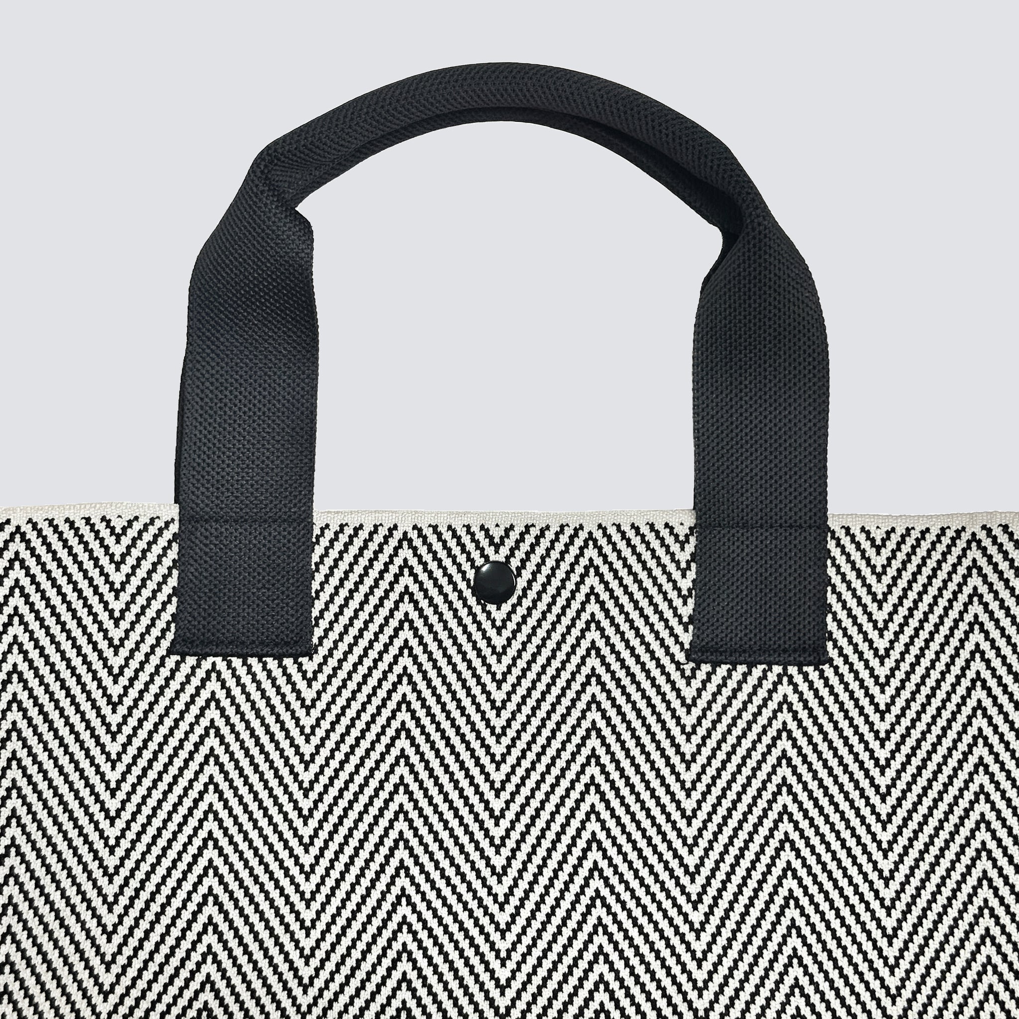 Black handle detail on a textured black and white knit tote bag