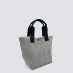 Side view of a textured black and white knit tote bag with black handles