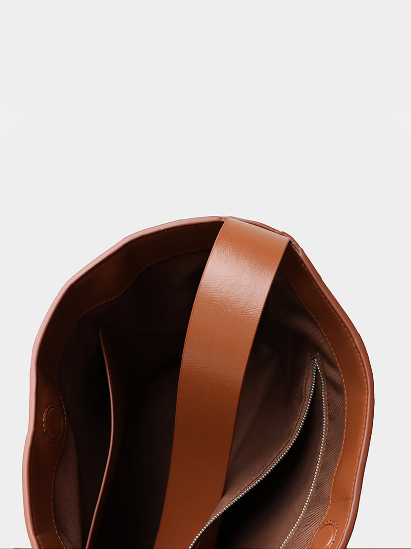 Inside view of the woven leather shoulder bag showing a premium fabric lining, a secure zipper pocket, and the sturdy wide leather strap.