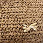 Macro detail of the natural paper straw weave and a gold-tone metallic accent