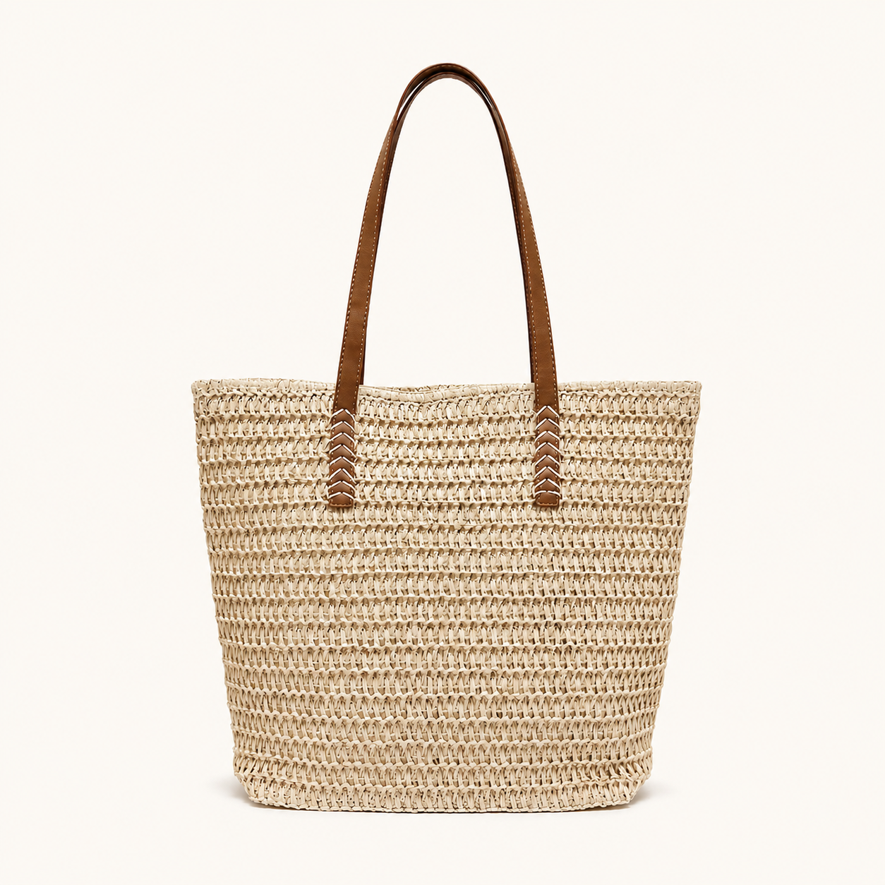 Front view of a light beige woven paper straw tote bag with brown vegan leather straps