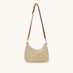 Front view of a natural woven paper straw crossbody beach bag with a long brown strap