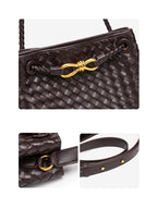Close-up of gold-tone drawstring detail side hardware and long strap on woven vegan leather bucket bag