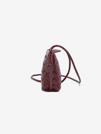 Side profile of the slim yet expandable woven vegan leather mini bag in rich dark burgundy.