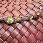 Macro detail of the burgundy woven vegan leather pattern and braided strap with decorative beads