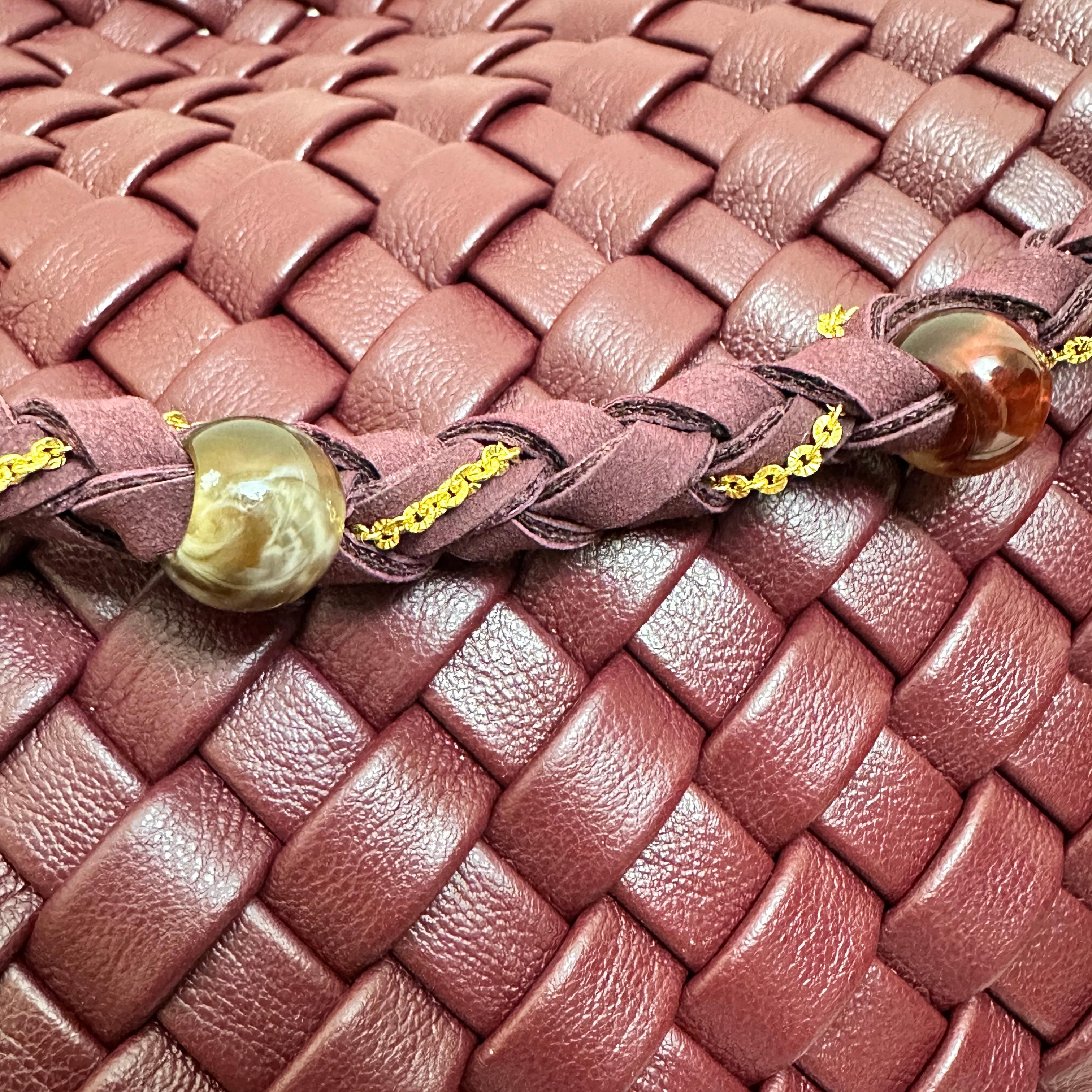 Macro detail of the burgundy woven vegan leather pattern and braided strap with decorative beads