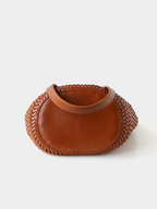 Bottom view of the brown artisan woven vegan leather bucket bag, highlighting the sturdy solid oval base for reliable structural support.